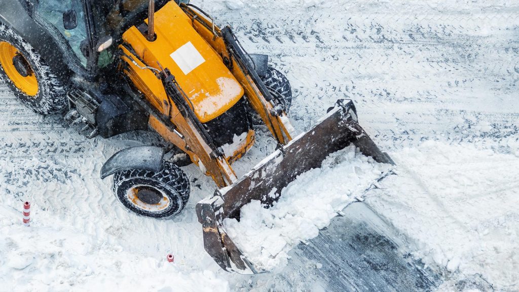 tractor removing snow from commercial property parking lot in winter